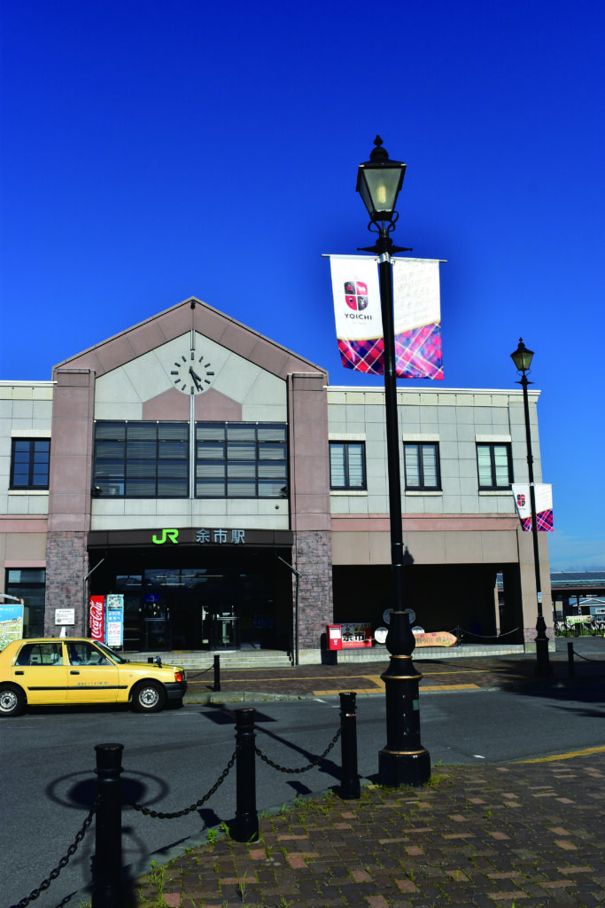 JR余市駅と青空を背景にたなびく余市タータン旗の画像